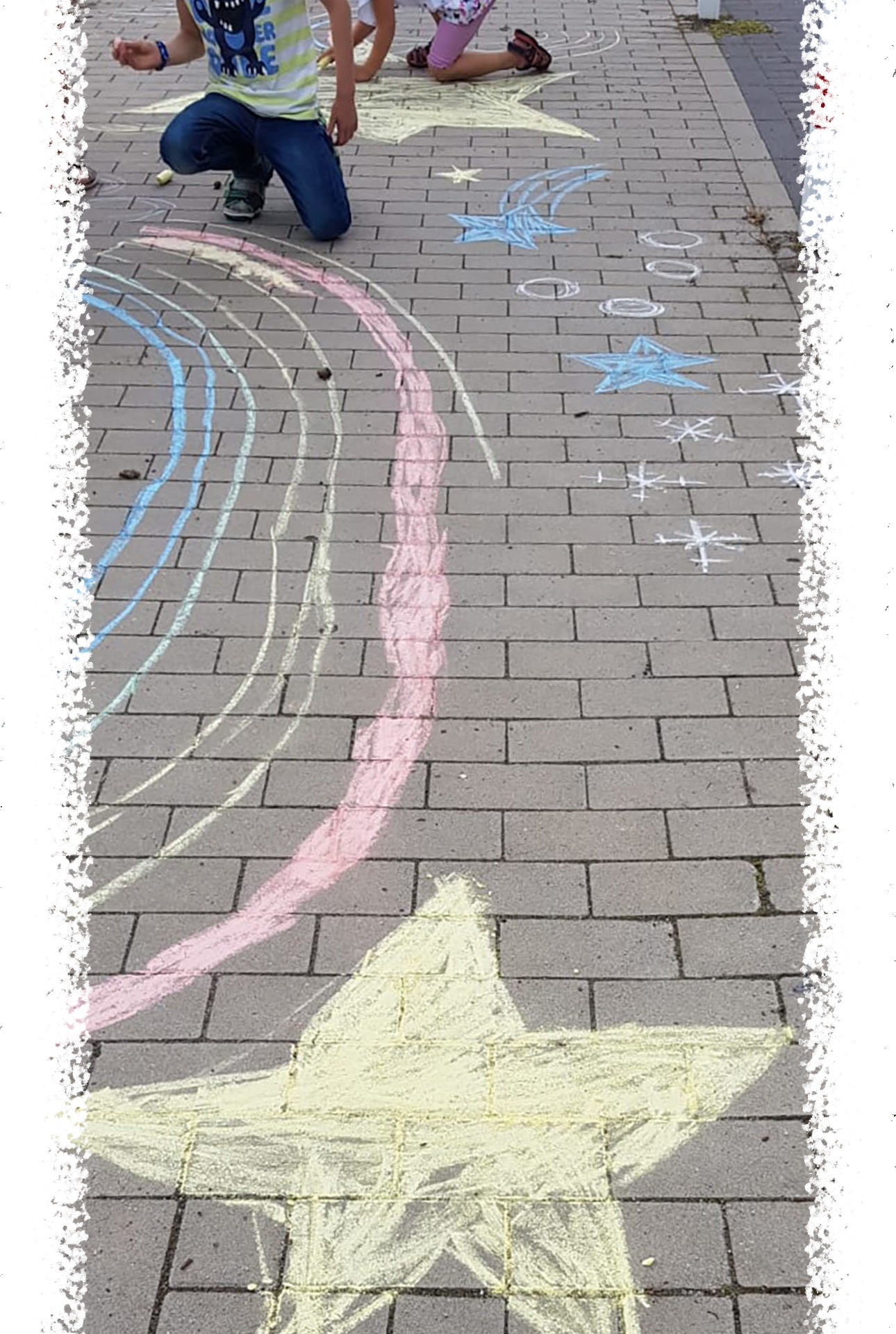 Regenbogen und Stern mit Kreide auf Gehweg gemalt